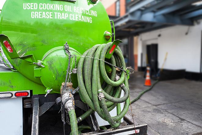 a professional plumber using a pump to empty a grease trap in Carlisle OH